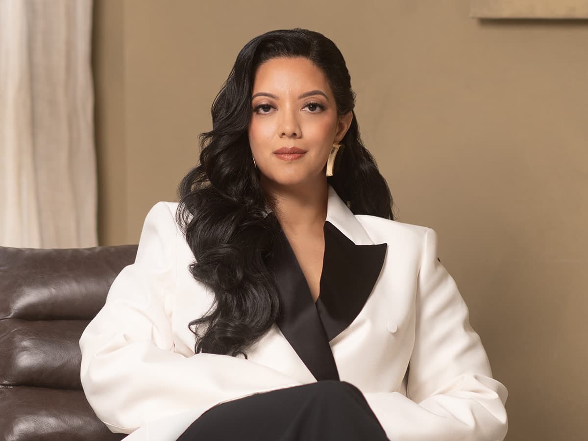 Priscilla Laclé seated in a white suit
